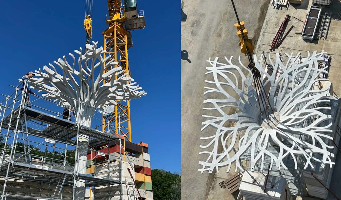 Große weiße Stahlstruktur mit verzweigten Armen wird per Kran auf Gerüst montiert.