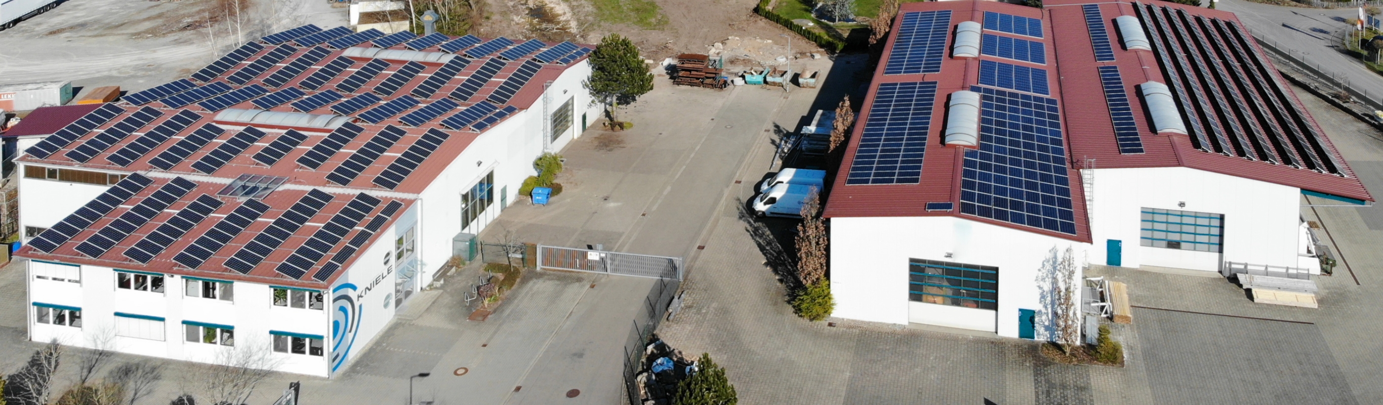 Vogelperspektive der Fertigungshallen von Kniele mit PV-Anlage auf dem Dach, Kniele Logo am Verwaltungsgebaeude.