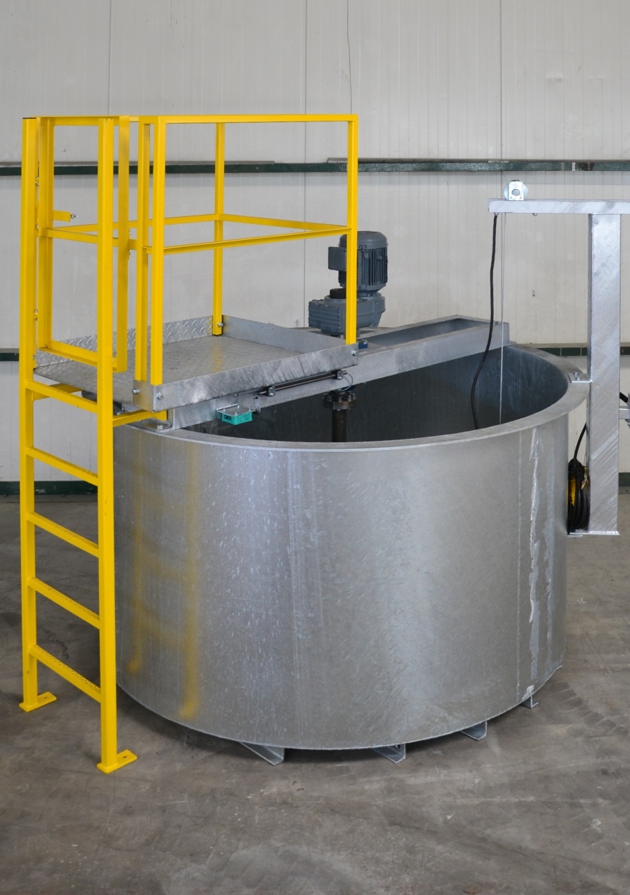 Cylindrical galvanized container with a drive in the middle and a yellow ladder on a pedestal on the container.