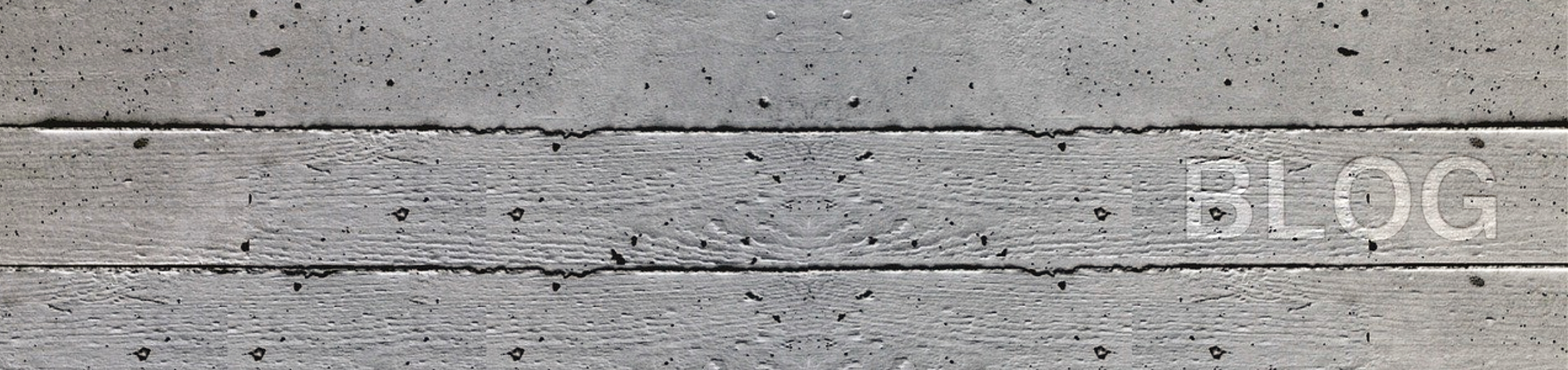 Graue Betonwand mit Poren und horizontalen Rillen.